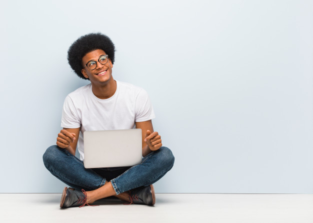 young-black-man-sitting-floor-with-laptop-dreaming-achieving-goals-purposes_1187-19949-2